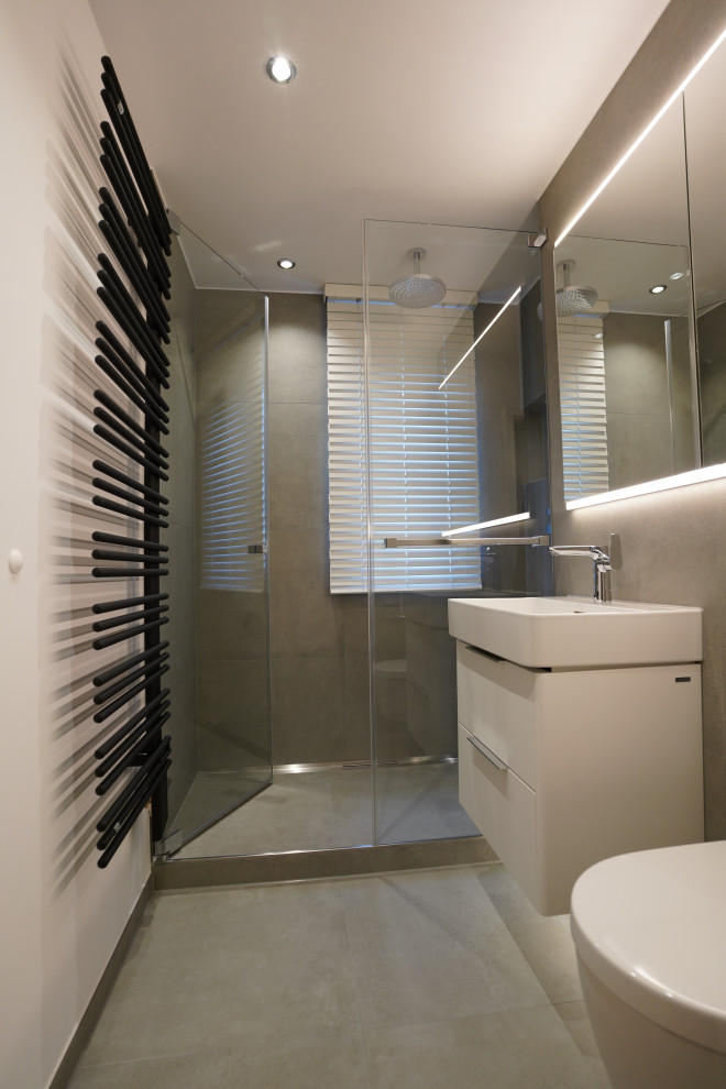 This is an example of a small contemporary shower room bathroom in Munich with flat-panel cabinets, white cabinets, an alcove shower, a wall mounted toilet, grey tiles, white walls, a wall-mounted sink, grey floors, a hinged door and a single sink.