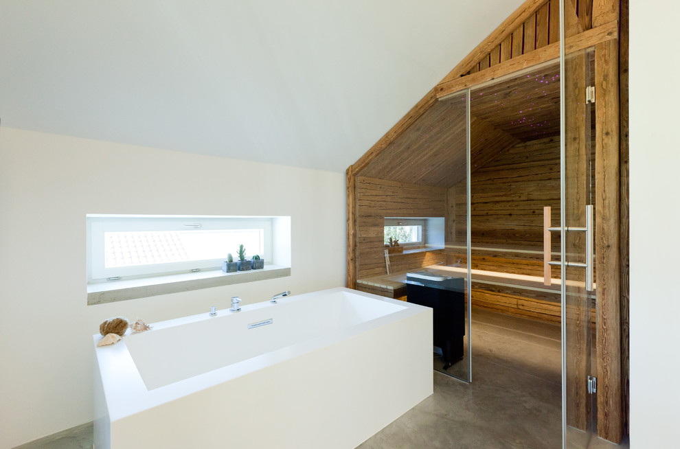 Immagine di una sauna minimal di medie dimensioni con vasca freestanding, pareti bianche, pavimento in cemento e pavimento grigio