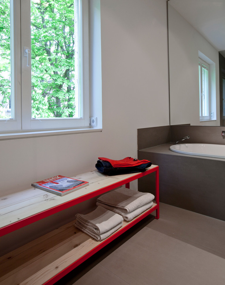 This is an example of a medium sized contemporary ensuite bathroom in Frankfurt with flat-panel cabinets, a built-in bath, a built-in shower, a wall mounted toilet, grey tiles, ceramic tiles, grey walls, ceramic flooring and a wall-mounted sink.