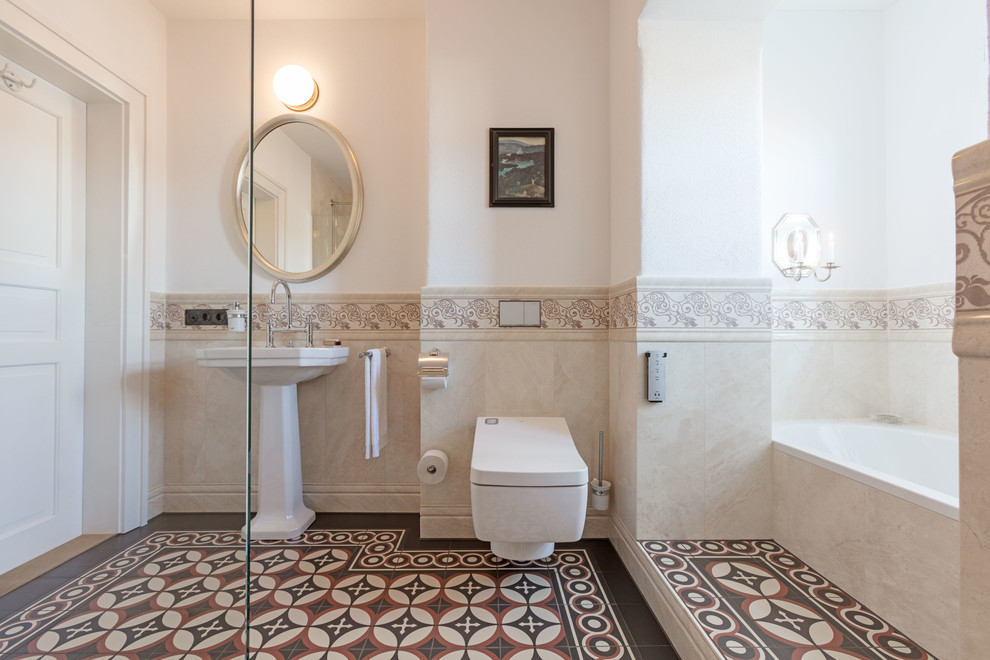 Foto på ett stort vintage badrum med dusch, med ett platsbyggt badkar, en kantlös dusch, en vägghängd toalettstol, beige kakel, beige väggar, ett piedestal handfat, beiget golv, med dusch som är öppen och klinkergolv i keramik