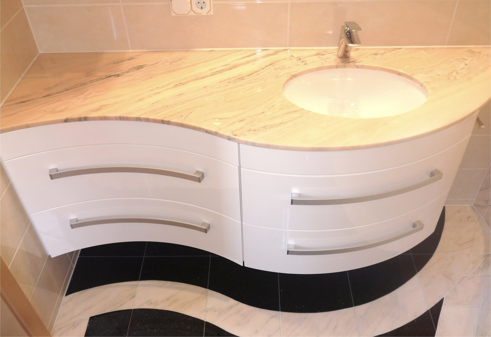 Cette photo montre une petite salle de bain tendance avec des portes de placard blanches, un carrelage beige, des carreaux de céramique, un sol en marbre, un plan de toilette en marbre et un lavabo encastré.