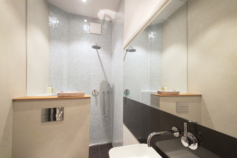 Immagine di una piccola stanza da bagno con doccia minimal con nessun'anta, ante in legno chiaro, doccia aperta, WC sospeso, piastrelle blu, piastrelle a mosaico, lavabo a bacinella e top in legno