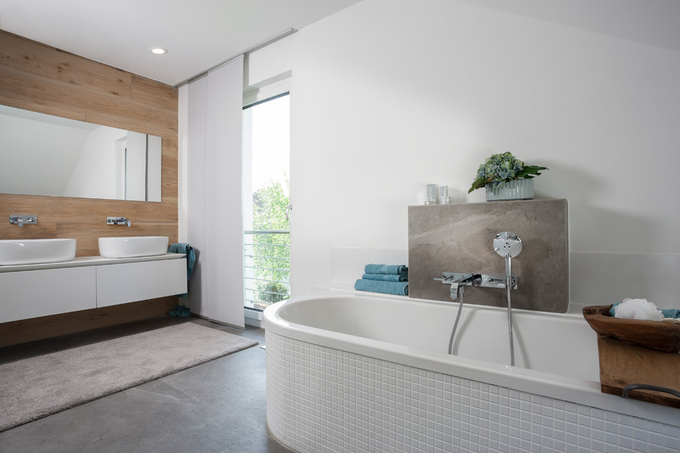 Medium sized contemporary shower room bathroom in Frankfurt with flat-panel cabinets, white cabinets, a freestanding bath, white walls, cement flooring, a vessel sink and grey floors.