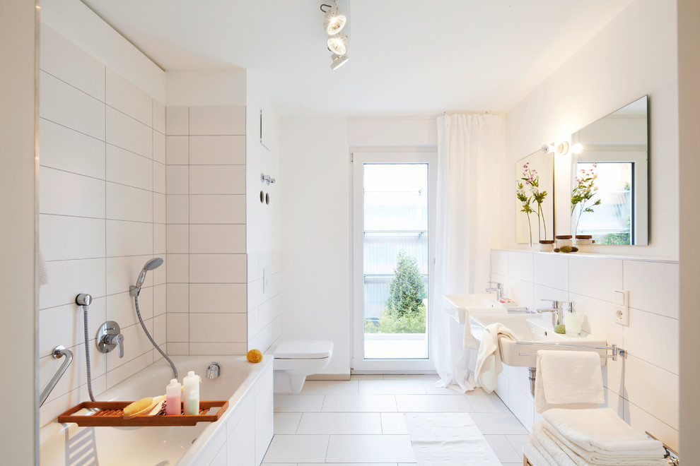 Свежая идея для дизайна: главная ванная комната среднего размера в современном стиле с подвесной раковиной, инсталляцией, белой плиткой, белыми стенами, накладной ванной, душем над ванной, керамической плиткой и полом из керамической плитки - отличное фото интерьера