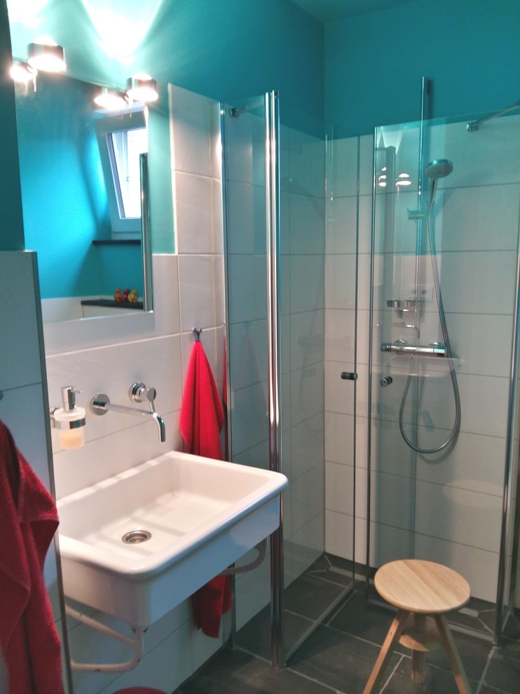 Kleines Modernes Duschbad mit bodengleicher Dusche, Wandtoilette mit Spülkasten, Steinfliesen, blauer Wandfarbe, Keramikboden und Wandwaschbecken in Hannover