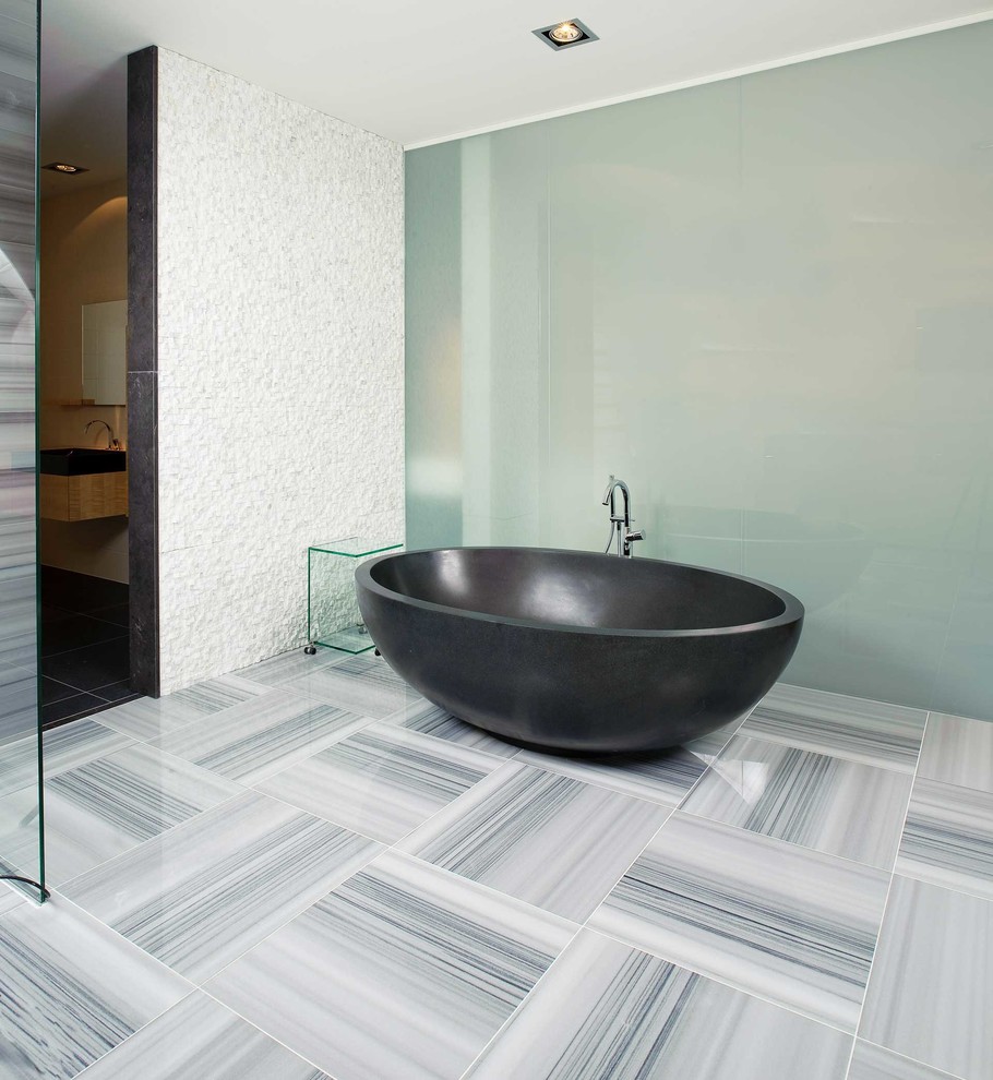 Foto de cuarto de baño contemporáneo con bañera exenta, baldosas y/o azulejos grises y paredes blancas