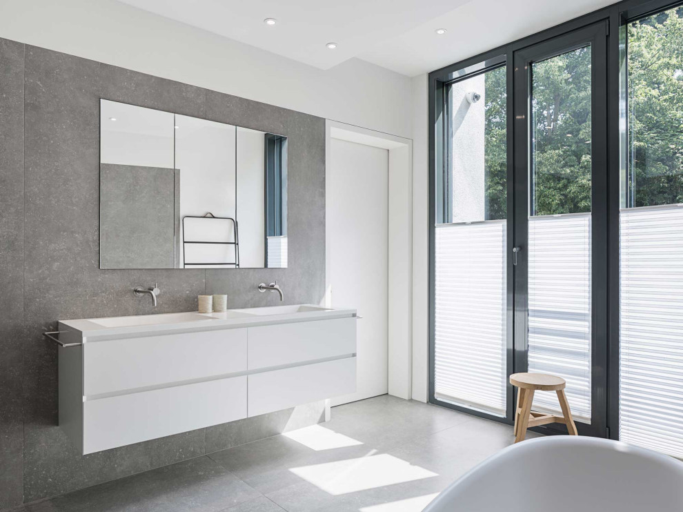 Modernes Badezimmer mit freistehender Badewanne, grauer Wandfarbe, Unterbauwaschbecken, Mineralwerkstoff-Waschtisch, grauem Boden und weißer Waschtischplatte in Sonstige