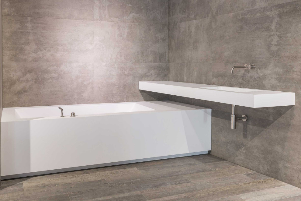 Idee per una stanza da bagno design con vasca da incasso, pareti grigie, top in superficie solida, pavimento marrone e top bianco