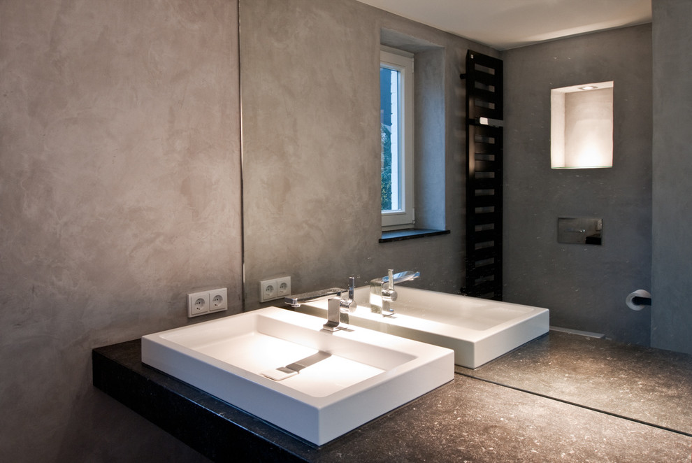 Ejemplo de cuarto de baño minimalista de tamaño medio con baldosas y/o azulejos negros, losas de piedra, paredes grises y encimera de granito