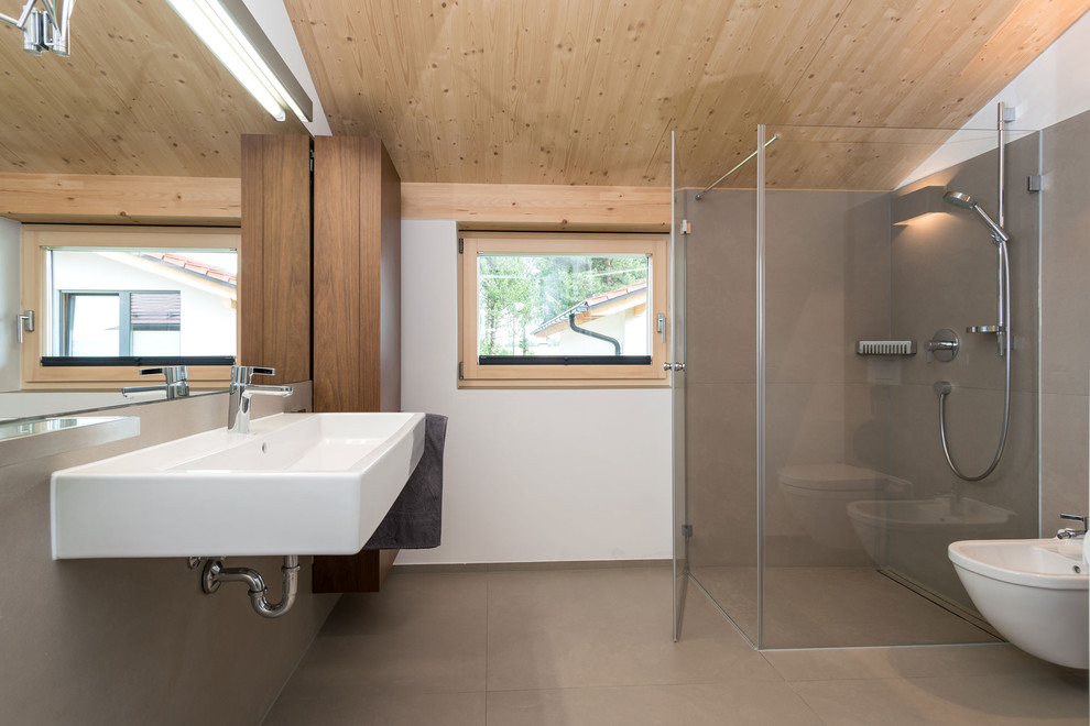 Idee per una stanza da bagno contemporanea di medie dimensioni con lavabo sospeso, doccia ad angolo, piastrelle grigie, pareti bianche, ante lisce, ante in legno scuro, bidè e pavimento in cemento