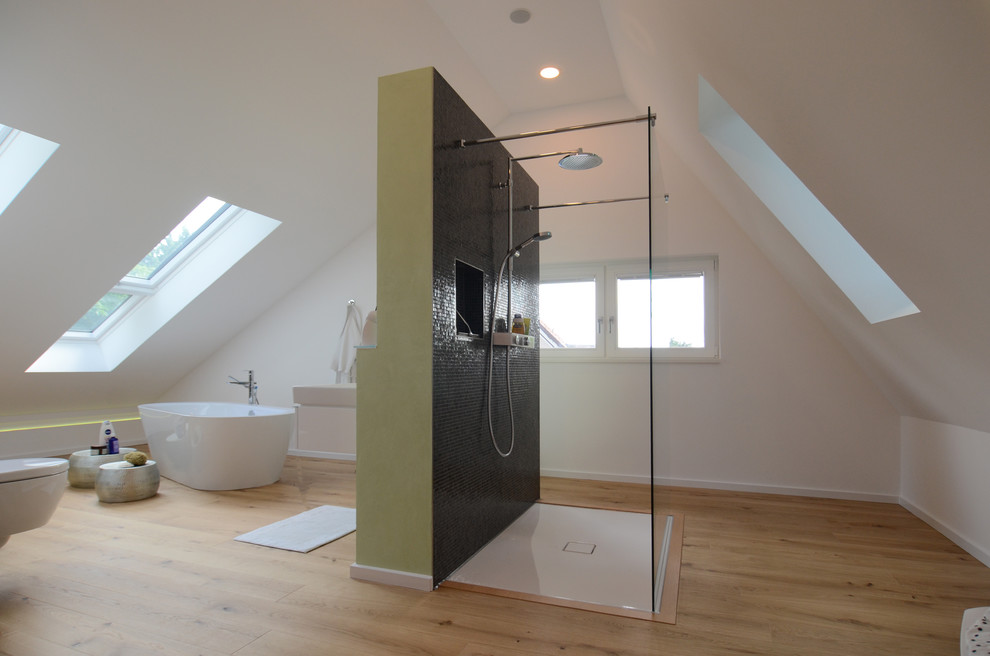 Источник вдохновения для домашнего уюта: огромная ванная комната в современном стиле с отдельно стоящей ванной, черной плиткой, плиткой мозаикой, белыми стенами, паркетным полом среднего тона и настольной раковиной