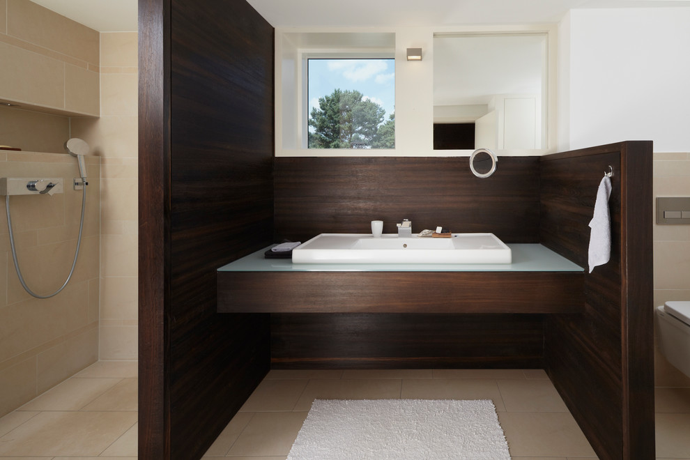 На фото: большая ванная комната в современном стиле с душем в нише, инсталляцией, бежевой плиткой, каменной плиткой, белыми стенами, полом из известняка, душевой кабиной, настольной раковиной и стеклянной столешницей с