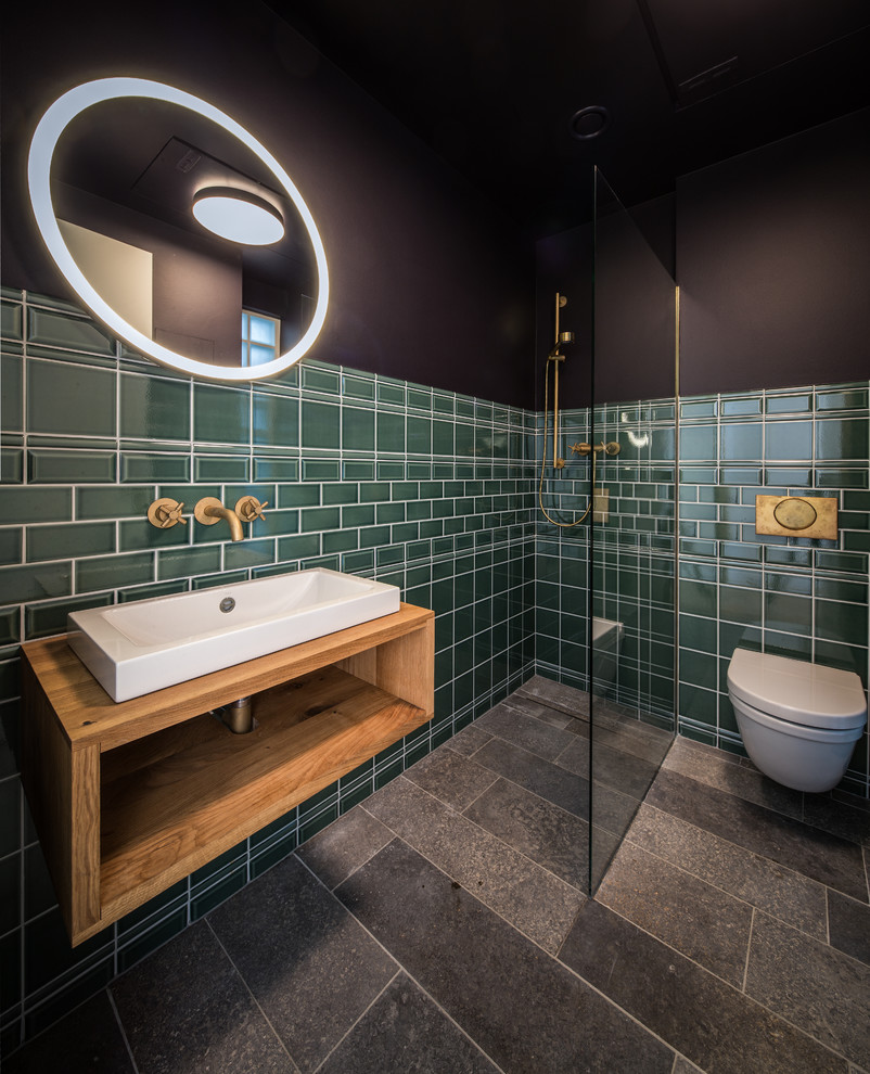 Inspiration for a small contemporary bathroom in Frankfurt with open cabinets, medium wood cabinets, a walk-in shower, a wall mounted toilet, green tiles, metro tiles, black walls, a vessel sink, wooden worktops and an open shower.