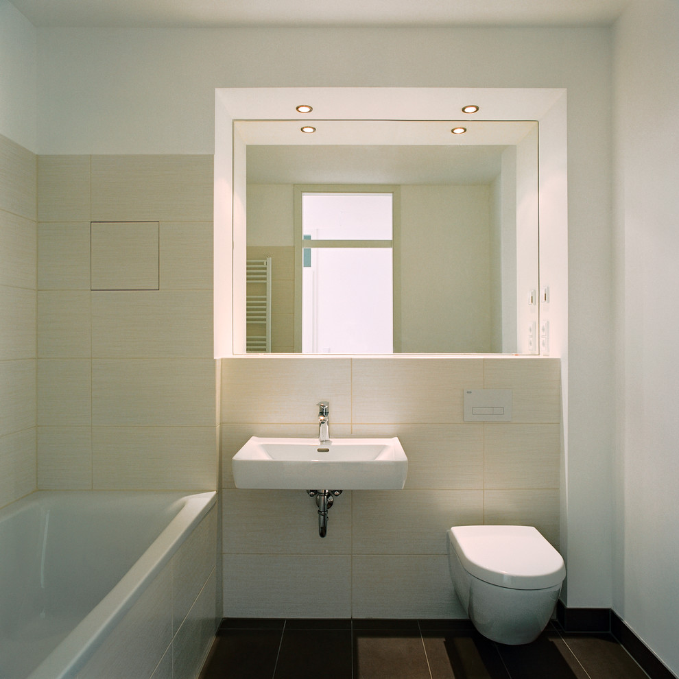 Modernes Badezimmer mit Wandwaschbecken, Badewanne in Nische, bodengleicher Dusche, Wandtoilette, beigen Fliesen, Steinfliesen und weißer Wandfarbe in Berlin