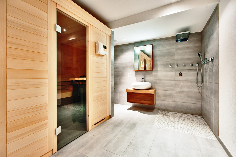 Пример оригинального дизайна: большая главная ванная комната в современном стиле с столешницей из дерева, открытым душем, серой плиткой, керамической плиткой, полом из керамической плитки, плоскими фасадами, темными деревянными фасадами, серыми стенами, настольной раковиной и открытым душем