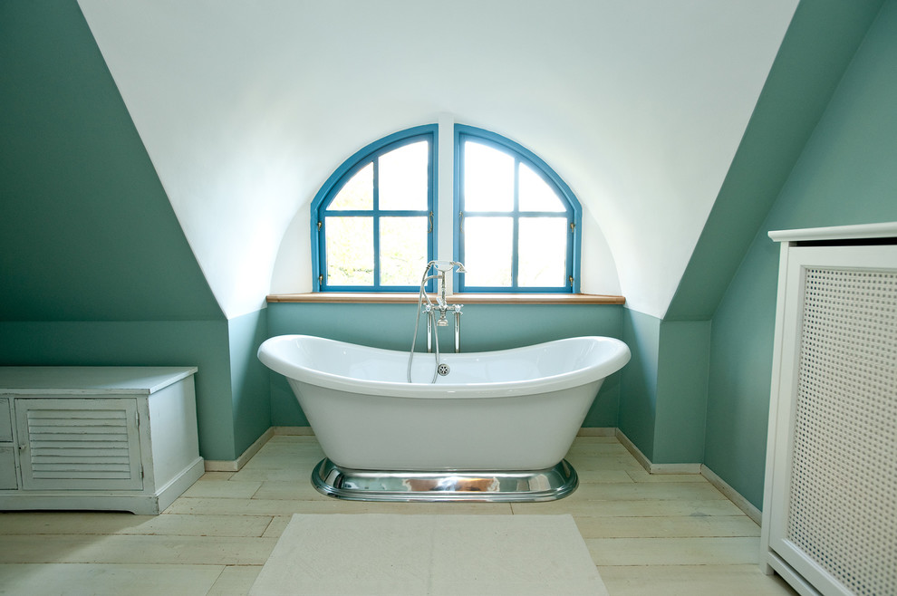 Foto på ett stort lantligt badrum, med skåp i slitet trä, ett fristående badkar, gröna väggar, ljust trägolv och luckor med lamellpanel