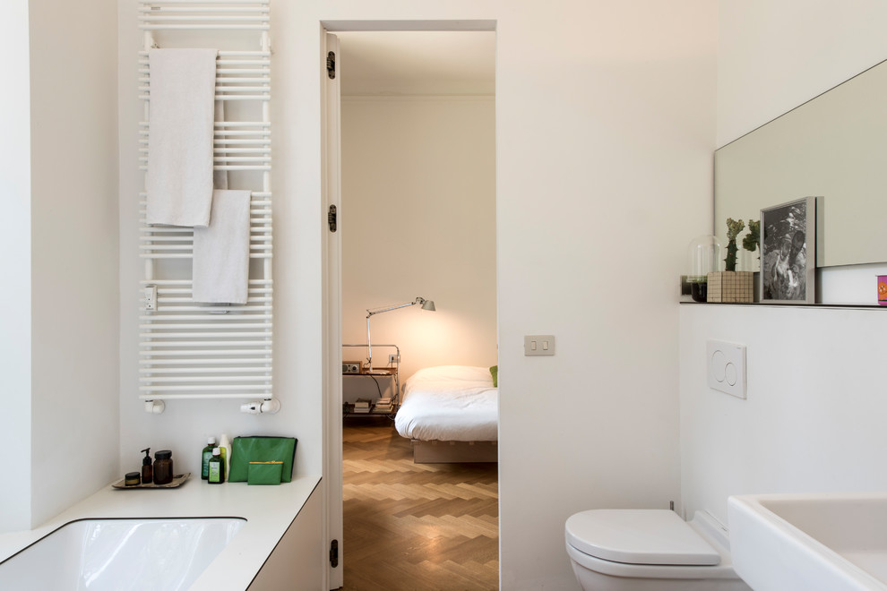 Idées déco pour une petite salle de bain principale contemporaine avec une baignoire posée, un carrelage blanc, un mur blanc, un sol en bois brun, un lavabo suspendu, un plan de toilette en stratifié et un plan de toilette blanc.