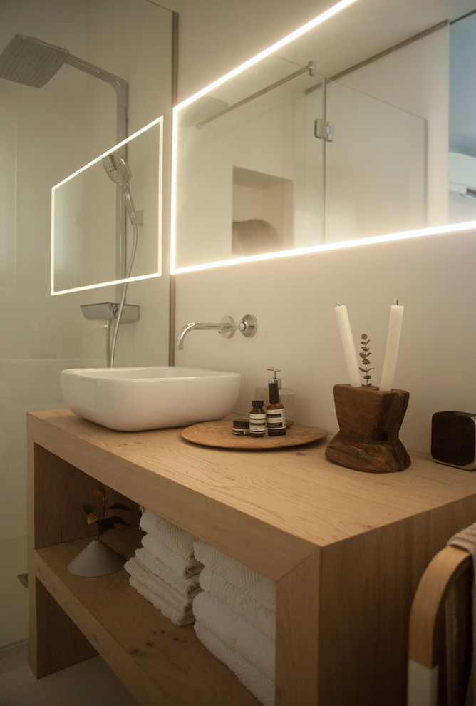 Exempel på ett mellanstort medelhavsstil badrum med dusch, med öppna hyllor, skåp i ljust trä, vit kakel, ett fristående badkar, en kantlös dusch, en vägghängd toalettstol, kakelplattor, bruna väggar, ljust trägolv, ett fristående handfat, träbänkskiva, brunt golv och med dusch som är öppen