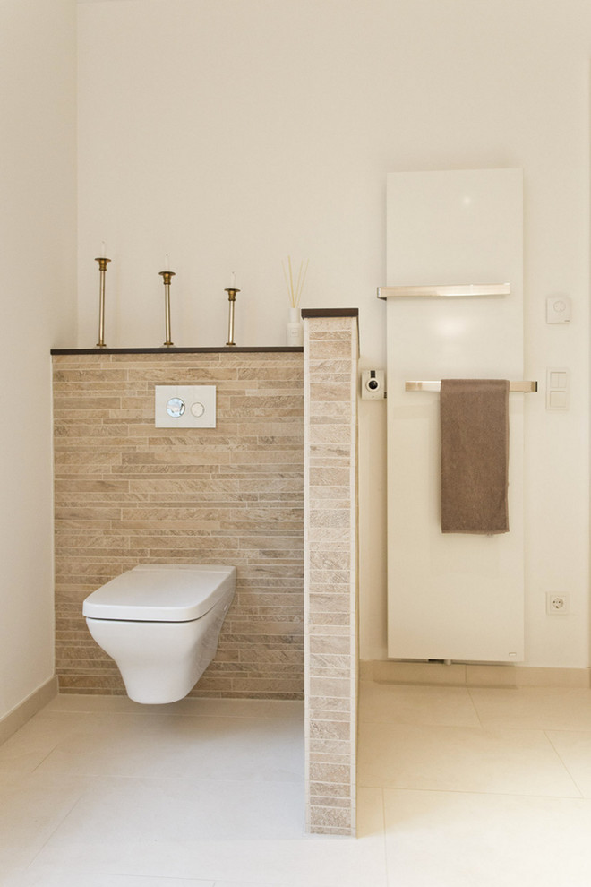 Design ideas for a contemporary bathroom in Hamburg with a wall mounted toilet, beige tiles, brown tiles, white walls, matchstick tiles and limestone flooring.