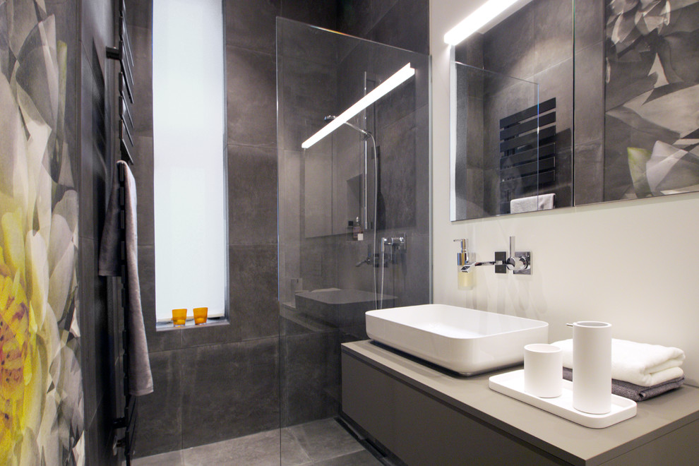 Inredning av ett modernt litet grå grått badrum med dusch, med släta luckor, grå skåp, en öppen dusch, en vägghängd toalettstol, grå kakel, vita väggar, ett fristående handfat, grått golv och med dusch som är öppen