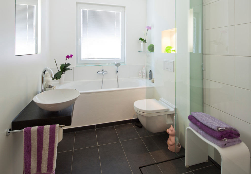 Modern inredning av ett stort en-suite badrum, med släta luckor, vita skåp, ett platsbyggt badkar, en öppen dusch, en toalettstol med separat cisternkåpa, grön kakel, glasskiva, vita väggar, marmorgolv, ett fristående handfat och granitbänkskiva