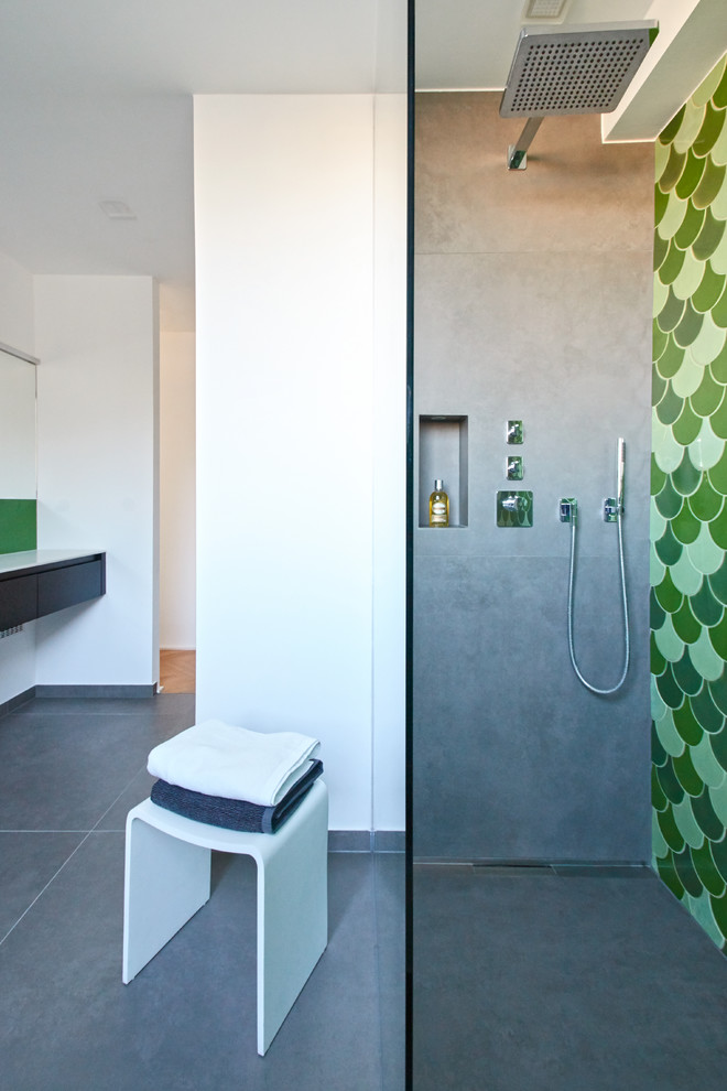 Mittelgroßes Modernes Duschbad mit flächenbündigen Schrankfronten, schwarzen Schränken, offener Dusche, grünen Fliesen, weißer Wandfarbe, integriertem Waschbecken, Mineralwerkstoff-Waschtisch, grauem Boden, offener Dusche und weißer Waschtischplatte in Berlin