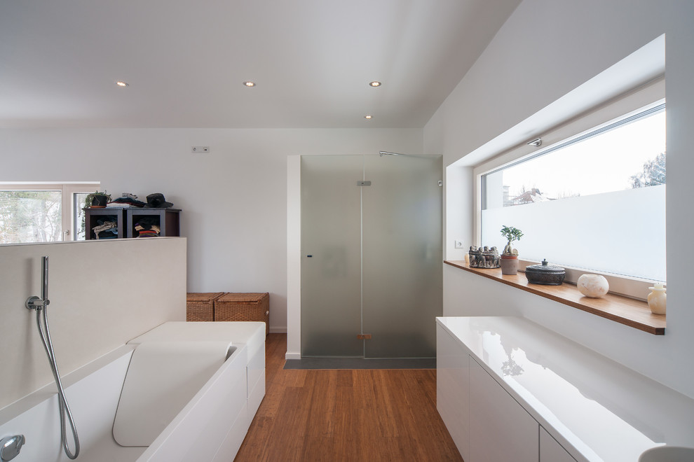 Bild på ett funkis en-suite badrum, med släta luckor, vita skåp, en kantlös dusch, vita väggar och mellanmörkt trägolv