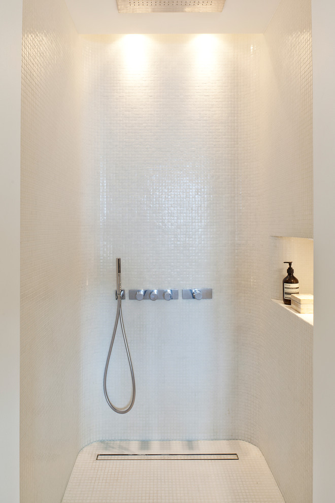 Exempel på ett mellanstort modernt en-suite badrum, med släta luckor, vita skåp, ett fristående badkar, en kantlös dusch, en vägghängd toalettstol, beige kakel, stenhäll, vita väggar, kalkstensgolv och ett fristående handfat