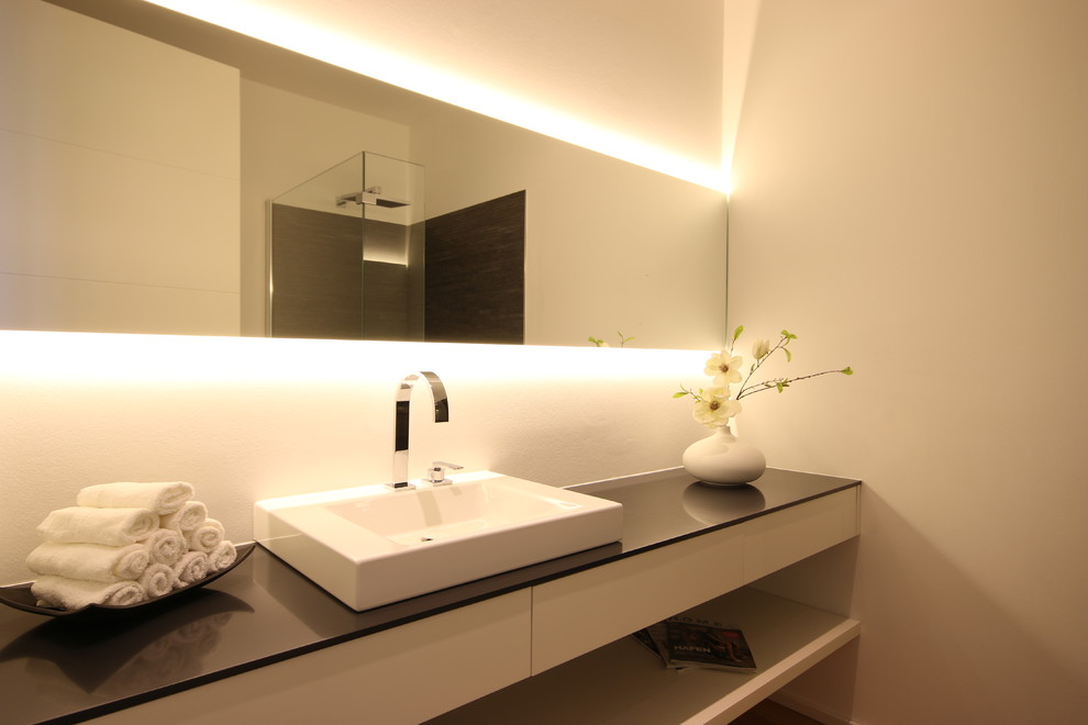 Example of a small trendy ceramic tile drop-in bathtub design in Leipzig with white walls, a vessel sink and white cabinets