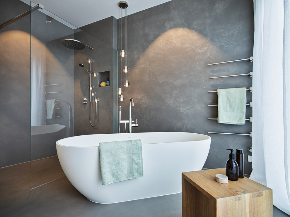 This is an example of a large ensuite bathroom in Frankfurt with a freestanding bath, a built-in shower, a wall mounted toilet, beige walls, concrete flooring, an integrated sink, beige floors, an open shower, a wall niche, a floating vanity unit and grey tiles.