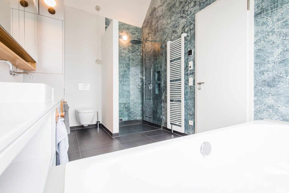 Photo of a medium sized scandi shower room bathroom in Munich with open cabinets, white cabinets, a built-in bath, a built-in shower, a two-piece toilet, white walls, cement flooring, a vessel sink, black floors, a hinged door and white worktops.