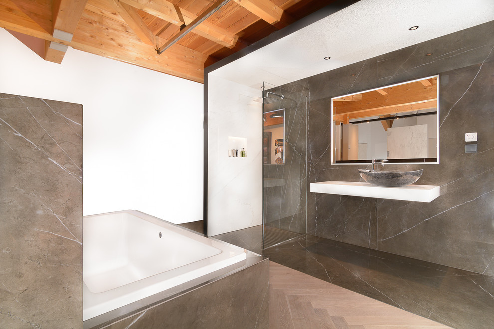 Idée de décoration pour une grande salle de bain principale design avec une baignoire posée, une douche ouverte, des dalles de pierre et une vasque.