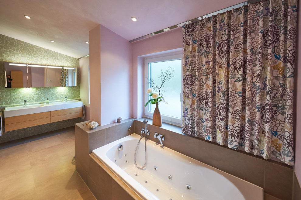 Свежая идея для дизайна: большая ванная комната в современном стиле с ванной в нише, серой плиткой, зеленой плиткой, розовыми стенами, раковиной с несколькими смесителями, фасадами цвета дерева среднего тона, керамической плиткой и зеркалом с подсветкой - отличное фото интерьера