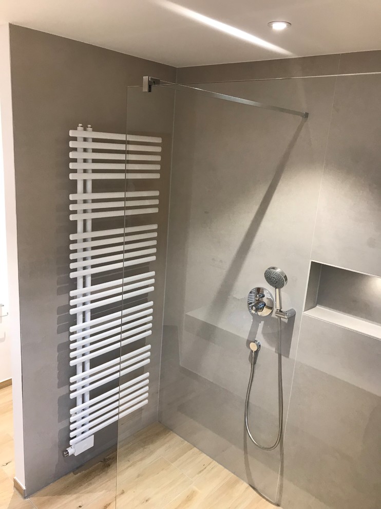 ライプツィヒにあるコンテンポラリースタイルのおしゃれな浴室 (ドロップイン型浴槽、バリアフリー、石スラブタイル、ベッセル式洗面器、引戸のシャワー) の写真