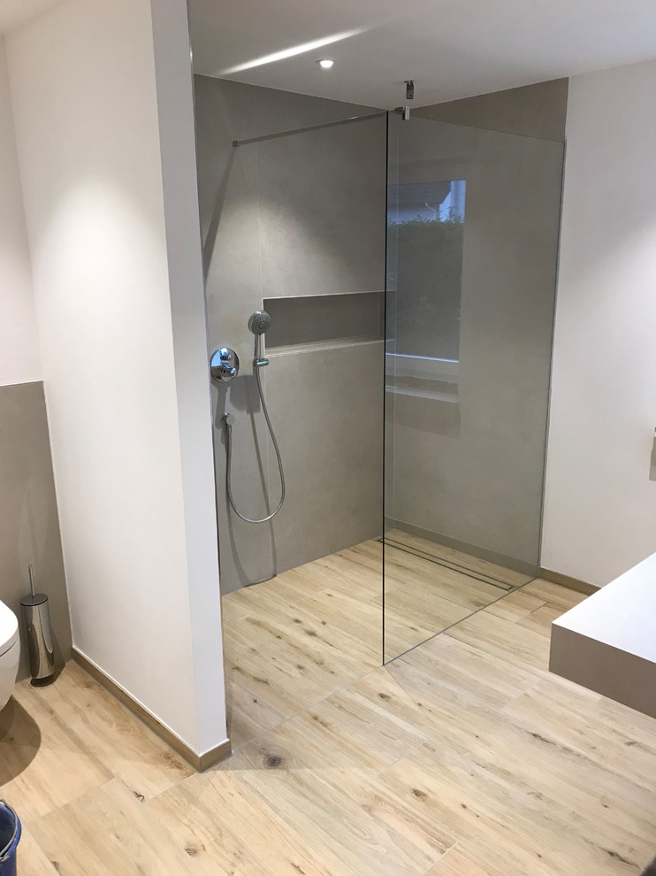 Modernes Badezimmer mit Einbaubadewanne, bodengleicher Dusche, Steinplatten, Aufsatzwaschbecken und Schiebetür-Duschabtrennung in Leipzig