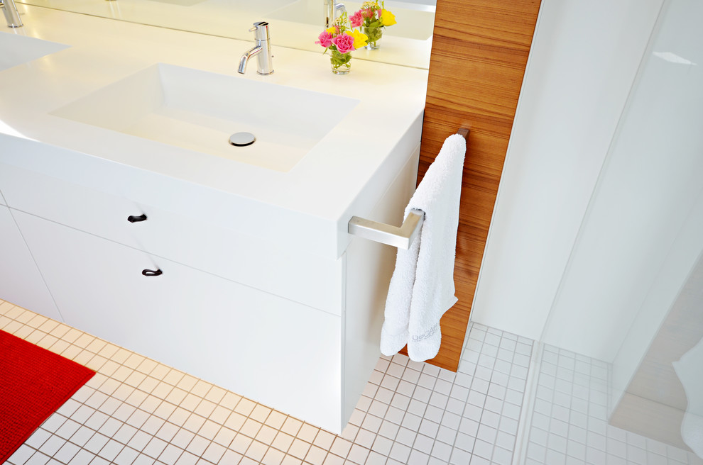 Cette photo montre une grande salle de bain tendance avec un plan de toilette en surface solide, des portes de placard blanches, une douche à l'italienne, un carrelage blanc, un mur blanc et une grande vasque.