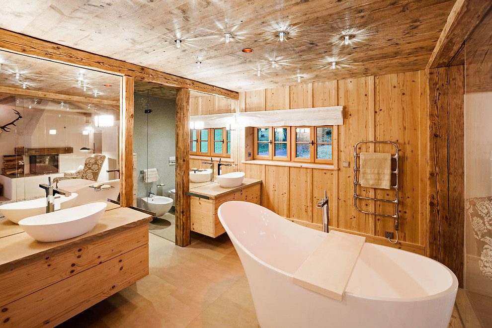 Пример оригинального дизайна: большая ванная комната: освещение в стиле кантри с фасадами цвета дерева среднего тона, отдельно стоящей ванной, коричневыми стенами, настольной раковиной, коричневым полом, плоскими фасадами и столешницей из дерева