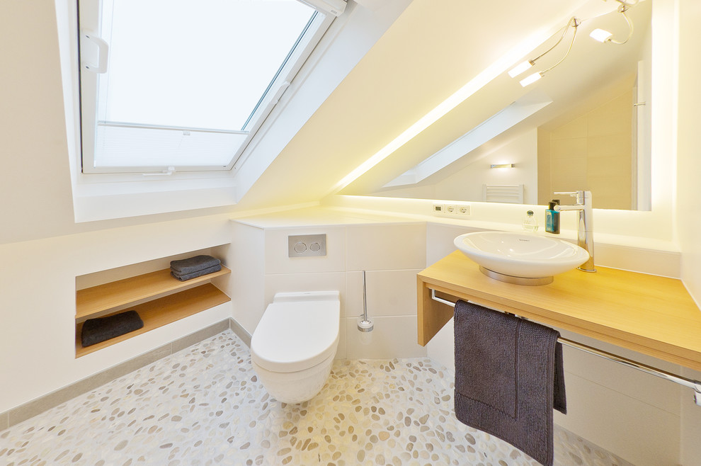 Idee per una piccola stanza da bagno padronale minimal con WC sospeso, piastrelle bianche, piastrelle di cemento, pareti bianche, pavimento con piastrelle di ciottoli, lavabo a bacinella e top in legno