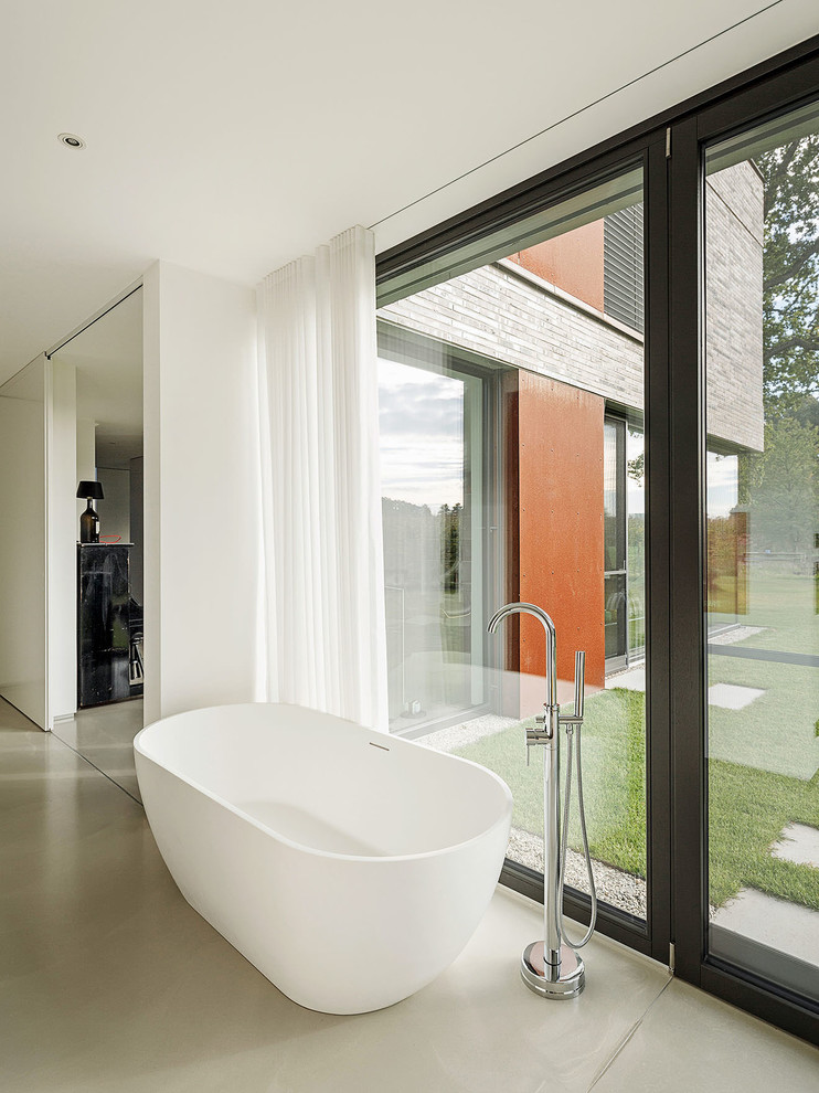 Пример оригинального дизайна: главная ванная комната среднего размера в стиле модернизм с отдельно стоящей ванной, белыми стенами, бетонным полом и серым полом