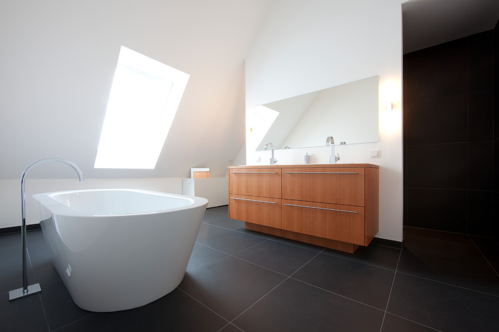Modern inredning av ett stort badrum, med släta luckor, skåp i mellenmörkt trä, ett fristående badkar och vita väggar