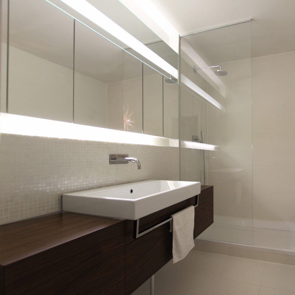 Пример оригинального дизайна: ванная комната среднего размера в классическом стиле с плоскими фасадами, темными деревянными фасадами, угловым душем, бежевой плиткой, плиткой мозаикой, белыми стенами, душевой кабиной, настольной раковиной и столешницей из дерева