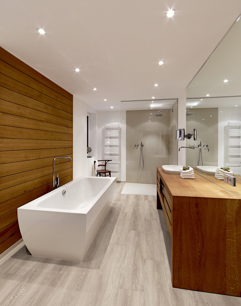 На фото: ванная комната в современном стиле с темными деревянными фасадами, отдельно стоящей ванной, душем без бортиков, полом из винила и серым полом с