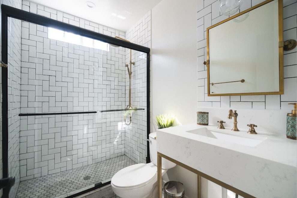 Пример оригинального дизайна: большая ванная комната в современном стиле с белыми фасадами, душем без бортиков, унитазом-моноблоком, белой плиткой, белыми стенами, душевой кабиной, монолитной раковиной, мраморной столешницей, душем с раздвижными дверями, белой столешницей, тумбой под одну раковину и встроенной тумбой