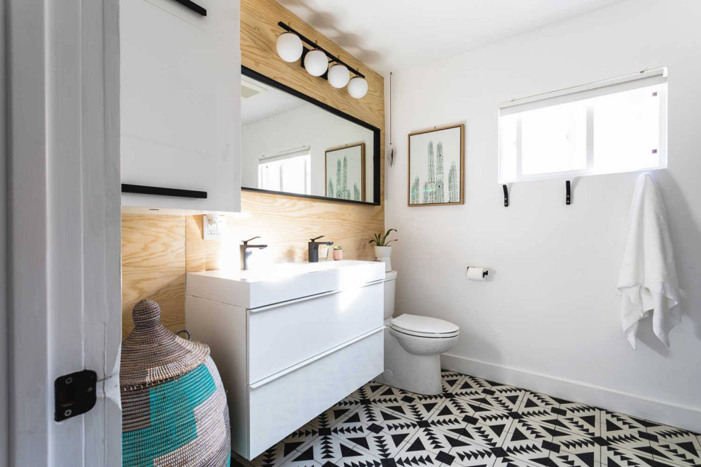 Mid-sized trendy 3/4 double-sink, multicolored floor and wood wall bathroom/laundry room photo in Other with flat-panel cabinets, white cabinets, a one-piece toilet, white walls, a vessel sink, wood countertops, white countertops and a built-in vanity
