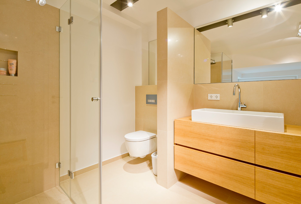 Cette image montre une salle de bain design en bois brun de taille moyenne avec une douche à l'italienne, WC suspendus, un carrelage beige, un mur blanc, une vasque, un placard à porte plane, un sol en carrelage de céramique et un plan de toilette en bois.