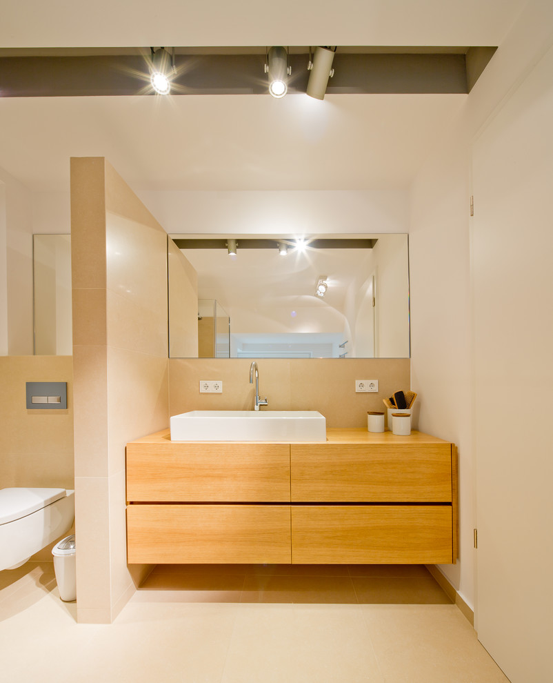 Cette image montre une salle de bain beige et blanche design en bois brun de taille moyenne avec un placard à porte plane, WC suspendus, des carreaux de céramique, un mur blanc, un sol en carrelage de céramique, une vasque et un plan de toilette en bois.