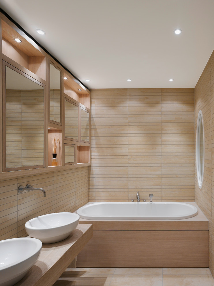 Bild på ett litet funkis en-suite badrum, med ett fristående handfat, skåp i ljust trä, träbänkskiva, beige kakel, ett badkar i en alkov, stickkakel, beige väggar och luckor med infälld panel