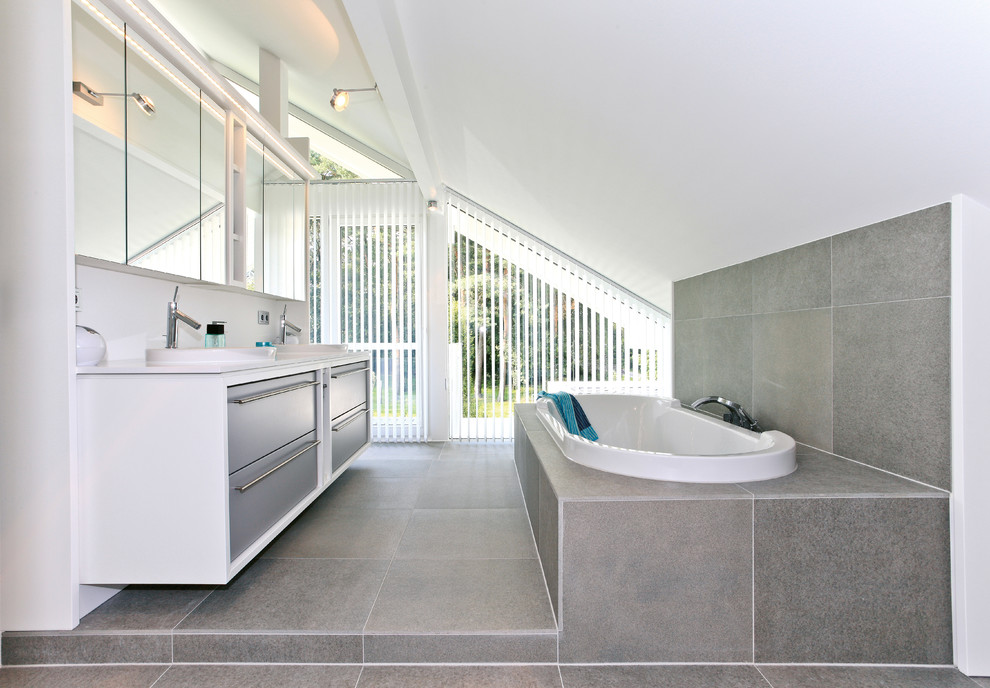 Exempel på ett mellanstort modernt badrum med dusch, med släta luckor, grå skåp, ett platsbyggt badkar, grå kakel, stenkakel, vita väggar, ett nedsänkt handfat, grått golv och cementgolv