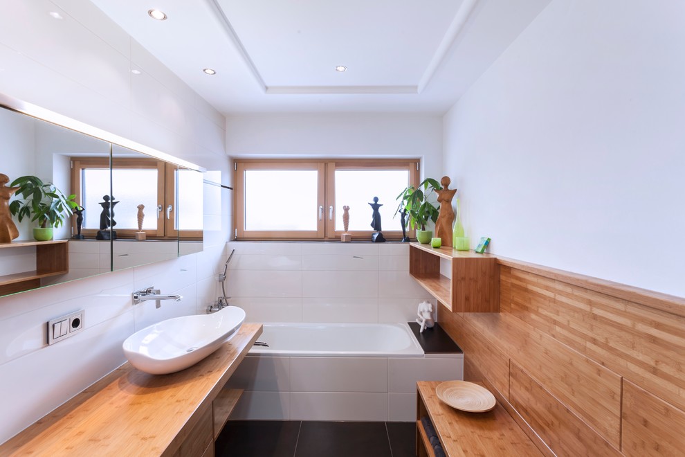 На фото: главная ванная комната в современном стиле с плоскими фасадами, фасадами цвета дерева среднего тона, накладной ванной, белыми стенами, настольной раковиной и столешницей из дерева