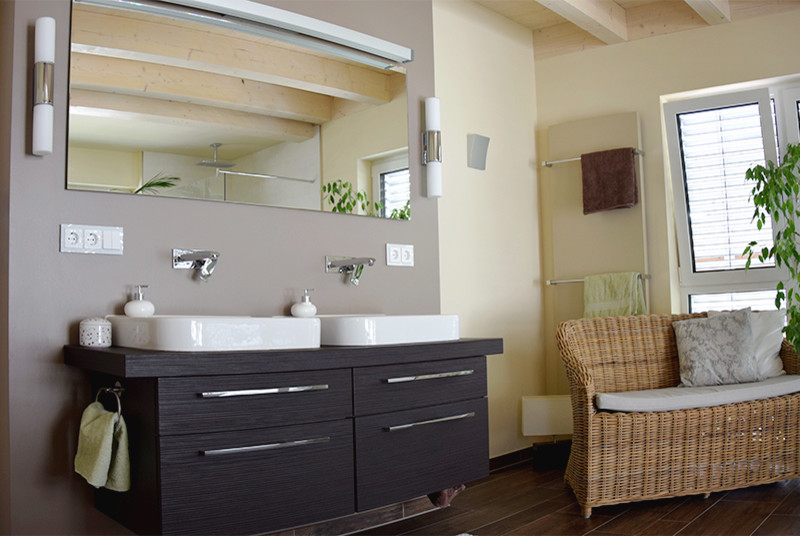 Foto de cuarto de baño actual de tamaño medio con puertas de armario negras, paredes grises, lavabo sobreencimera y suelo marrón
